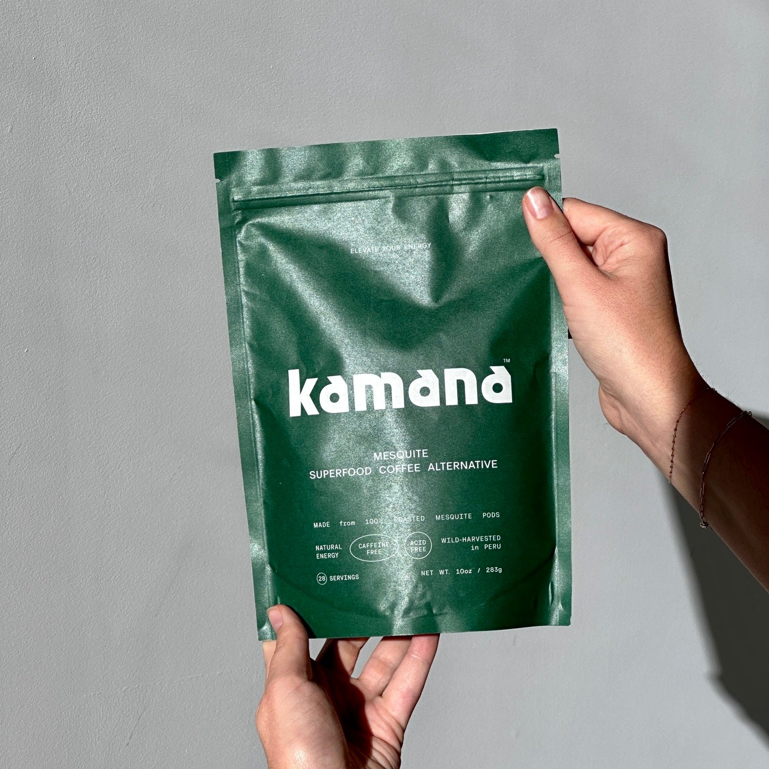 Kamand mesquite superfood coffee alternative pouch held against a minimalist gray background, promoting a healthy coffee substitute
